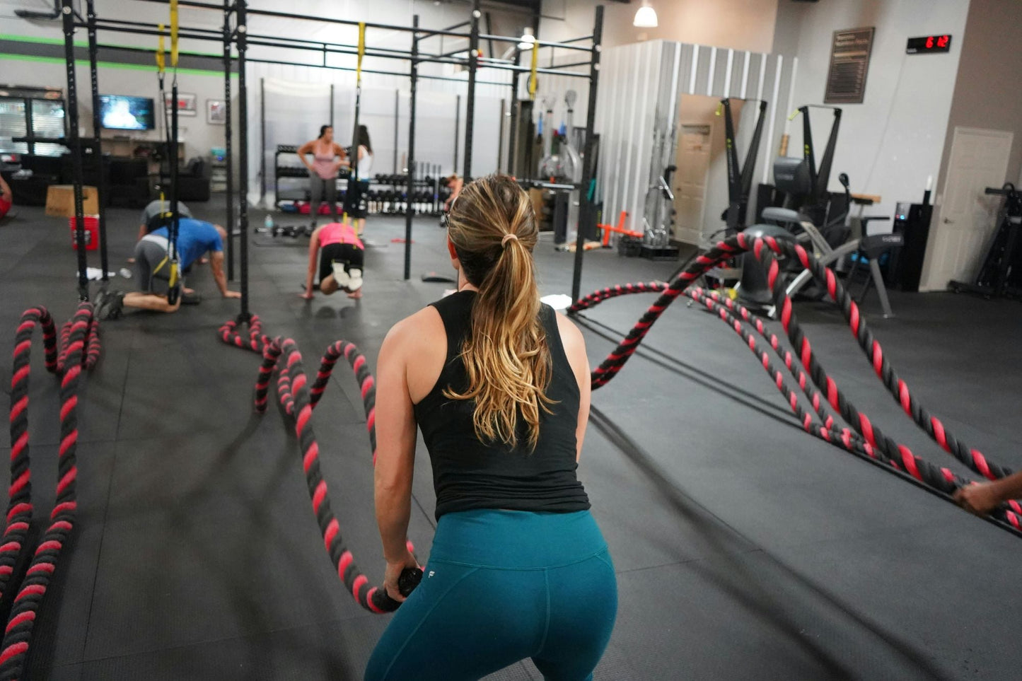 Woman working out with battle ropes in a gym, staying fresh and odor-free with stick deodorant.